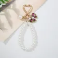 Detail view of handmade faux pearl bow keychain with heart clasp and rhinestones - Purple