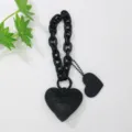Vista detallada de un llavero de corazón de cuero negro con cadena gruesa y patrón en relieve. - Negro