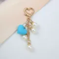 Détail en gros plan d'un cœur en caoutchouc bleu et de perles sur un porte-clés doré élégant. - Bleu lac