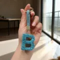 Detailed close-up of a teal blue rhinestone-studded letter B charm held in hand - Letter B