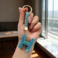 Close-up of a luxury blue rhinestone letter H keychain with a crystal-studded strap - Letter H