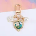 Detailed macro shot of heart and flower keychain with pearl charms for bag decoration - Teal