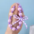 Close-up detail of a handmade purple beaded phone strap featuring a bow and cute charm - Purple