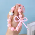 Detailed view of pink bow beaded keychain with heart charm detail and glossy pearls. - Pink