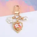 Elegant gold heart keychain featuring white enamel flower and pearl charm detail - Pink