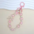 Close-up of a pink beaded keychain with cute bow and lucky clover charms for backpack. - Pink