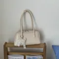 Cremefarbene Retro-Bowling-Handtasche mit Perlenbogen in Lifestyle-Umgebung - Mit Anhänger / Gebrochenes Weiß