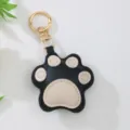 Close-up of cute black and beige leather cat paw keychain with gold-tone metal clasp - Black