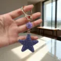 Close-up of purple rhinestone star keychain with sparkling crystal details and gold ring - Purple
