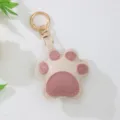 Detail of a cute pink and beige leather cat paw keychain with high-quality gold hardware - White