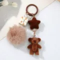 Close-up detail of cute brown flocking bear and star keychain with a soft fur ball - Brown Bear