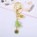 Detail view of cute green ceramic snake zodiac charm with golden bell on a keychain - Snake