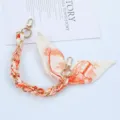 Detailed view of fashion phone strap featuring orange patterned scarf and gold chain - Style I