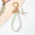 Close-up view of an elegant pearl letter K keychain with heart-shaped golden metal clasp. - Letter K Style / Pearl White