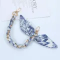 Close-up of blue and white patterned silk scarf phone strap with elegant golden chain - Style W