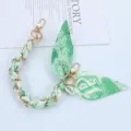 Detail of stylish green silk scarf interwoven with gold metal chain phone strap - Style P