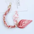 Detailed view of red and white silk scarf interwoven with a gold chain phone strap - Style A