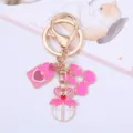 Close-up of pink enamel charms on a gold keychain for romantic Valentine's Day gifts - Cherry Style / Pink