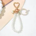 Close-up detail of a pearl-beaded keychain featuring a heart clasp and initial S charm - Letter Q Style / Pearl White