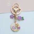 Detailed macro view of a gold cherry blossom keychain with purple enamel and pearls - Pearl Flower Style (A026) / Purple