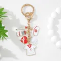 Detailed view of gold-tone medical keychain featuring nurse cap, mask and heart charms. - White