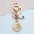 Detailed view of cherry blossom and pearl charms on a gold metal wreath keychain. - Pearl Flower Style (A026) / Pink