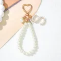 Close-up of pearl letter S keychain with gold heart buckle and handmade metal tag - Letter S Style / Pearl White