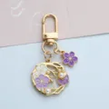 Close-up of gold-tone cherry blossom keychain with purple enamel flower and pearl accents - U-Clasp Style (A026) / Purple