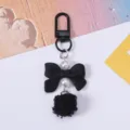 Close-up of cute black bow keychain with pearls and pompom detail - Black