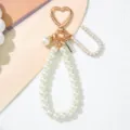 Close-up of elegant pearl keychain with golden heart clasp and engraved metal tag detail - Letter U Style / Pearl White