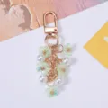 Detailed view of sweet green cherry blossom and pearl keychain with gold-toned metal clasp. - Green