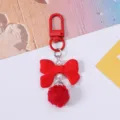 Close-up of a cute red resin bow keychain with white pearls and a soft red pom-pom. - Red