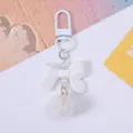 Detailed view of cute white resin bow keychain with faux pearls and soft fluffy pom-pom - White