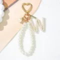 Close-up detail view of pearl letter M keychain with gold heart clasp and handmade tag - Letter W Style / Pearl White