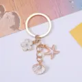 Close-up detail of ocean-themed alloy keychain with starfish, seashell, and pearl - White