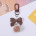 Close-up detail of cute brown resin bow keychain with pearls and soft fuzzy pom-pom pendant - Brown