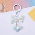 Detailed view of iridescent heart and bow keychain charm with elegant pearl accents - White