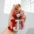 Vue détaillée de trois porte-clés lettre J en strass de couleurs rouge, argent et rose - Style J / Rose