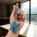 Detailed macro view of a blue rhinestone letter K keychain with premium gold hardware - Letter K