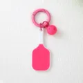 Détail d'un porte-clés rose avec raquette et balle de pickleball sur fond blanc - Rose rouge
