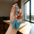 Detailed view of a sparkling blue rhinestone letter N keychain held in the sunlight - Letter N
