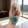 Macro detail of a sparkling blue rhinestone letter O keychain held by hand in light - Letter O