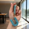 Close-up of a sparkling blue rhinestone letter U keychain held in a person's hand - Letter U