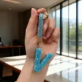 Close-up of a blue rhinestone-studded letter V keychain with gold-tone hardware - Letter V