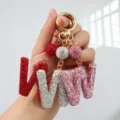 Gros plan détaillé de porte-clés étincelants en strass lettre 'W' en rouge, argent et rose - Motif W / Rose