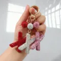 Détail de porte-clés en forme de lettre 'X' sertis de strass étincelants en plusieurs couleurs. - Motif X / Rose