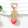 Close-up view of cute pink strawberry keychain featuring a gold bow and rhinestone details. - Plated Pink