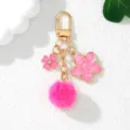Detailed view of a pink sakura enamel flower and soft faux fur pom-pom keychain charm - Rose Red