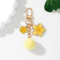 Detail view of Japanese style yellow flower keychain with soft pompom and gold hardware - Yellow