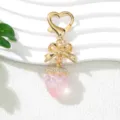 Detailed close-up view of a pink UV strawberry keychain with a golden bow charm. - UV Pink